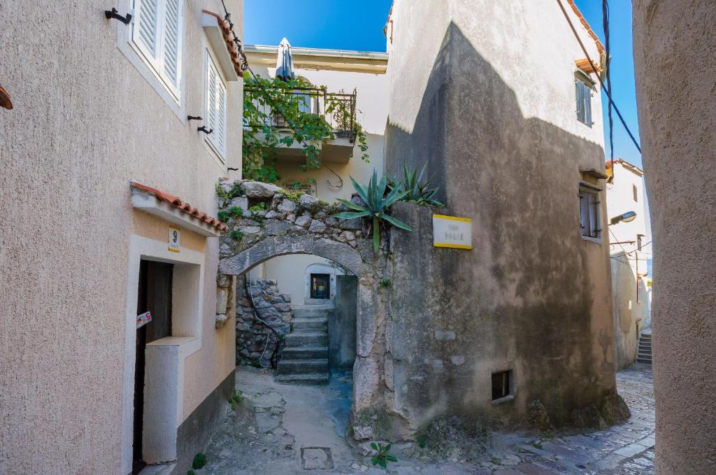 an alley between two buildings with an archway at Under Ancient Roofs Vrbnik in Vrbnik