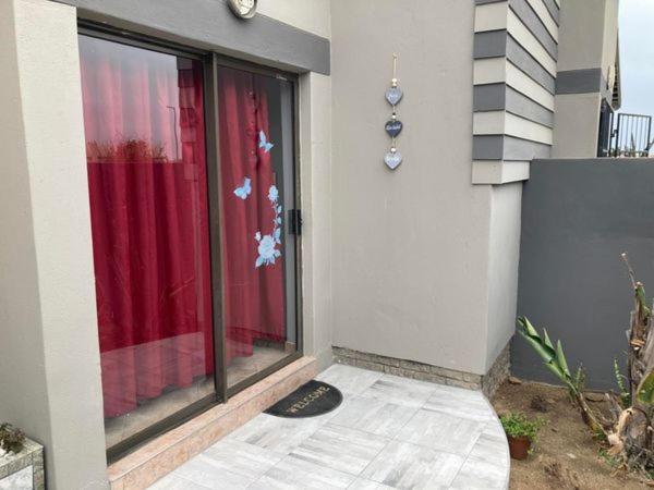 eine Tür zu einem Haus mit einer Flagge am Fenster in der Unterkunft Daffodil Self Catering and Accommodation B in Swakopmund