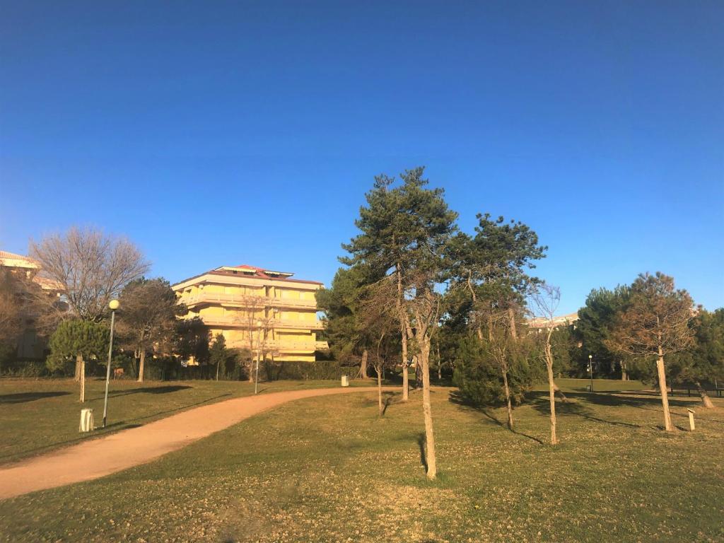 a path in a park with trees and a building at Silva - Appartamento in Bibione