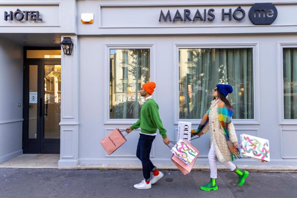 two people walking down the street with shopping bags at Hôtel Marais Hôme in Paris