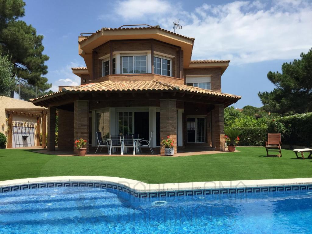 a villa with a swimming pool in front of a house at BarcelonaVacances-Villa Lucia in San Pol de Mar