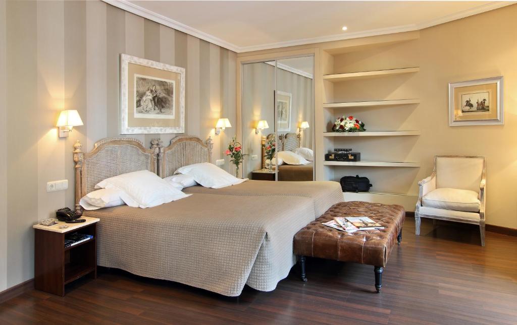 sypialnia z dużym łóżkiem i krzesłem w obiekcie Hotel Imperial w mieście Valladolid
