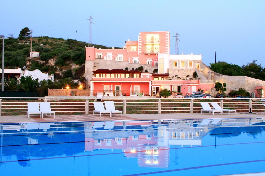 una piscina con sedie e un edificio sullo sfondo di Hotel Boutique Il Castellino Relais a Vieste