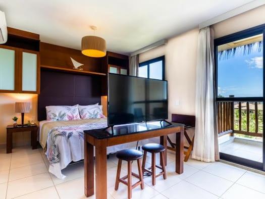 a bedroom with a bed and a desk with stools at VG SUN Apartamento com vista para o mar - High speed internet in Caucaia