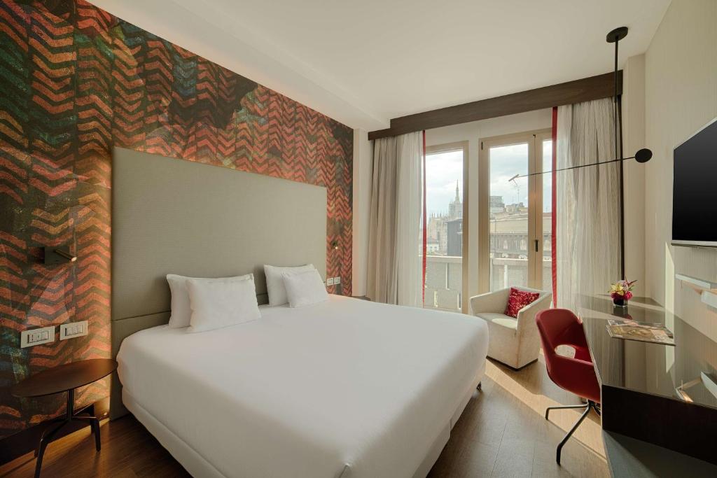 
a hotel room with a large bed and a large window at NH Collection Milano President in Milan
