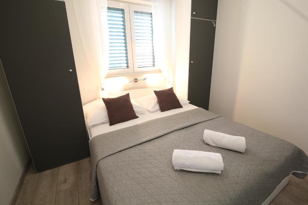 a bedroom with a bed with two pillows and a window at Apartments Viola in Tučepi