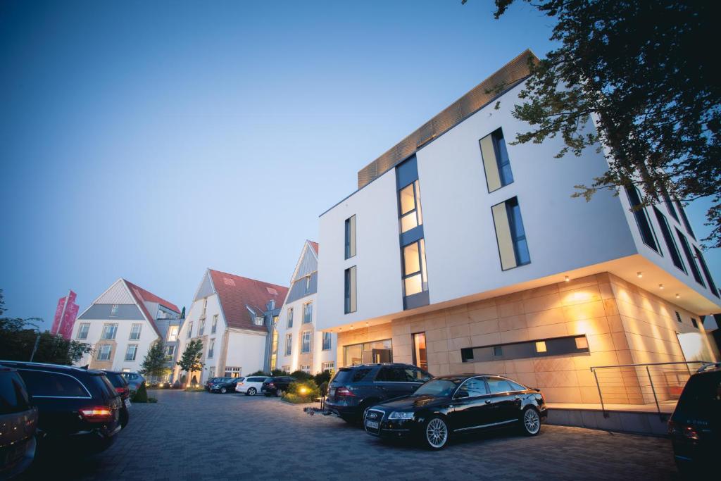 eine Gruppe von Autos, die vor einem Gebäude geparkt sind in der Unterkunft Lind Hotel in Rietberg