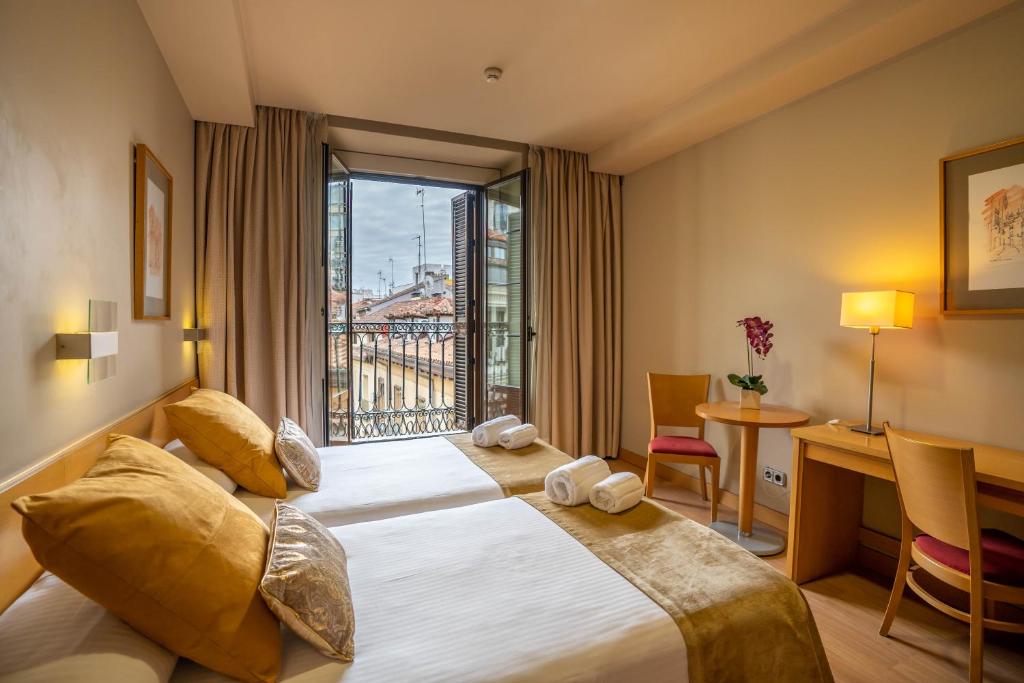 a hotel room with a bed and a desk and a window at Victoria 4 Puerta del Sol in Madrid
