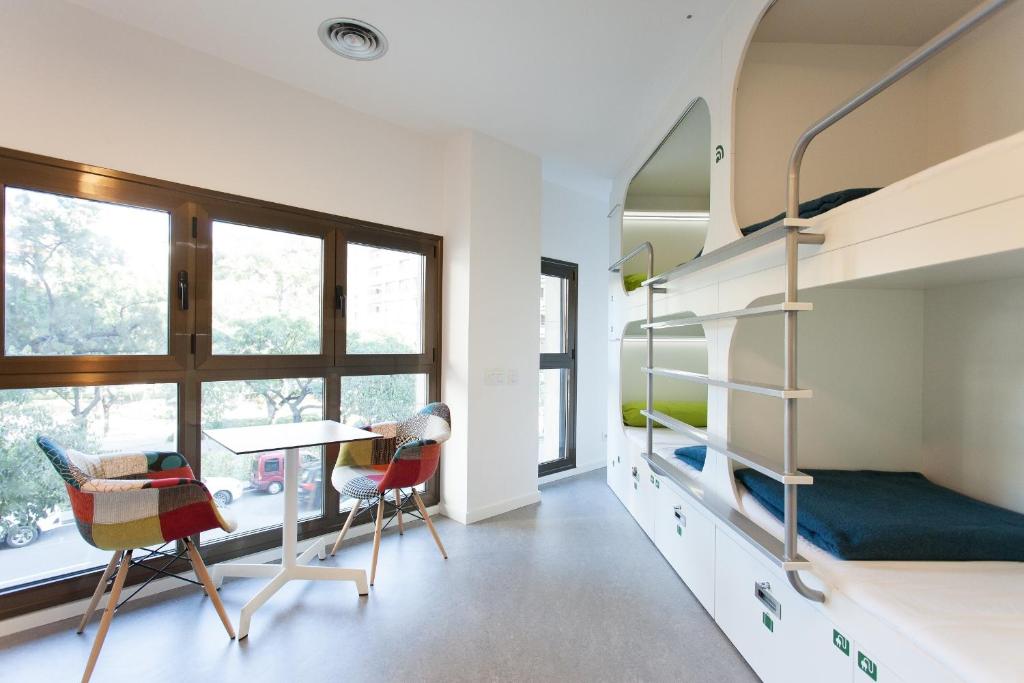 a bedroom with a bunk bed and a desk and chairs at Dream Cube Hostel in Barcelona