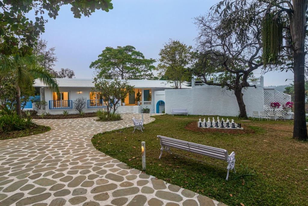 a park with a bench in front of a house at SaffronStays Kairos Zeus, Karjat - Greek style pool villa near Camp Max in Karjat