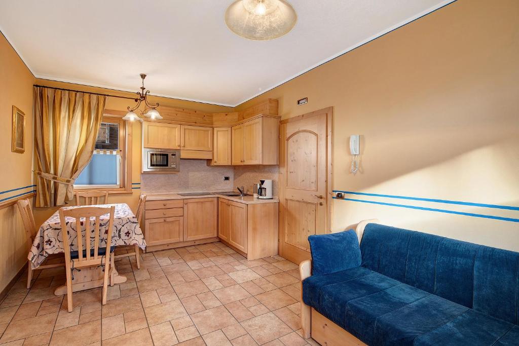 uma sala de estar com um sofá azul e uma cozinha em Chalet Betty Appartamento Pec em Livigno