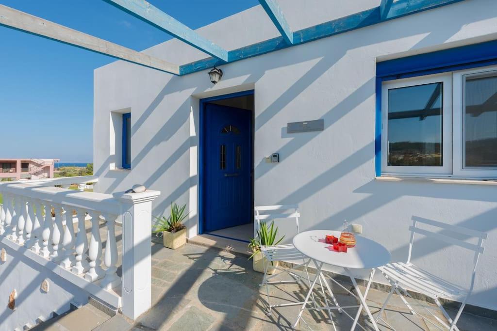 una casa blanca con una puerta azul y una mesa en The Citrus House, en Kalavárda