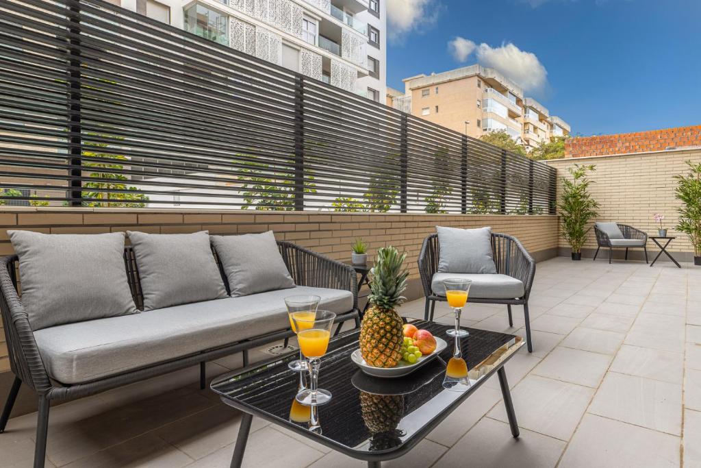 een patio met een bank en een fruitschaal op een tafel bij Living4Malaga Pacific Terrace Apartment in Málaga