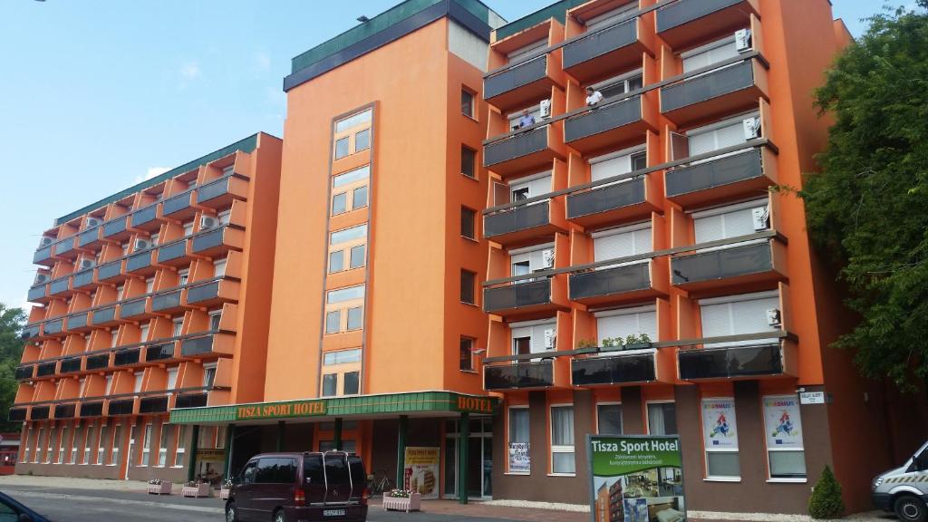 ein orangenes Gebäude mit einem Van davor in der Unterkunft Tisza Sport Hotel in Szeged