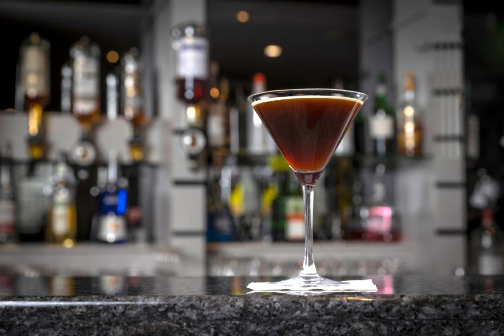 a drink in a martini glass sitting on a bar at Maldron Hotel Belfast International Airport in Aldergrove