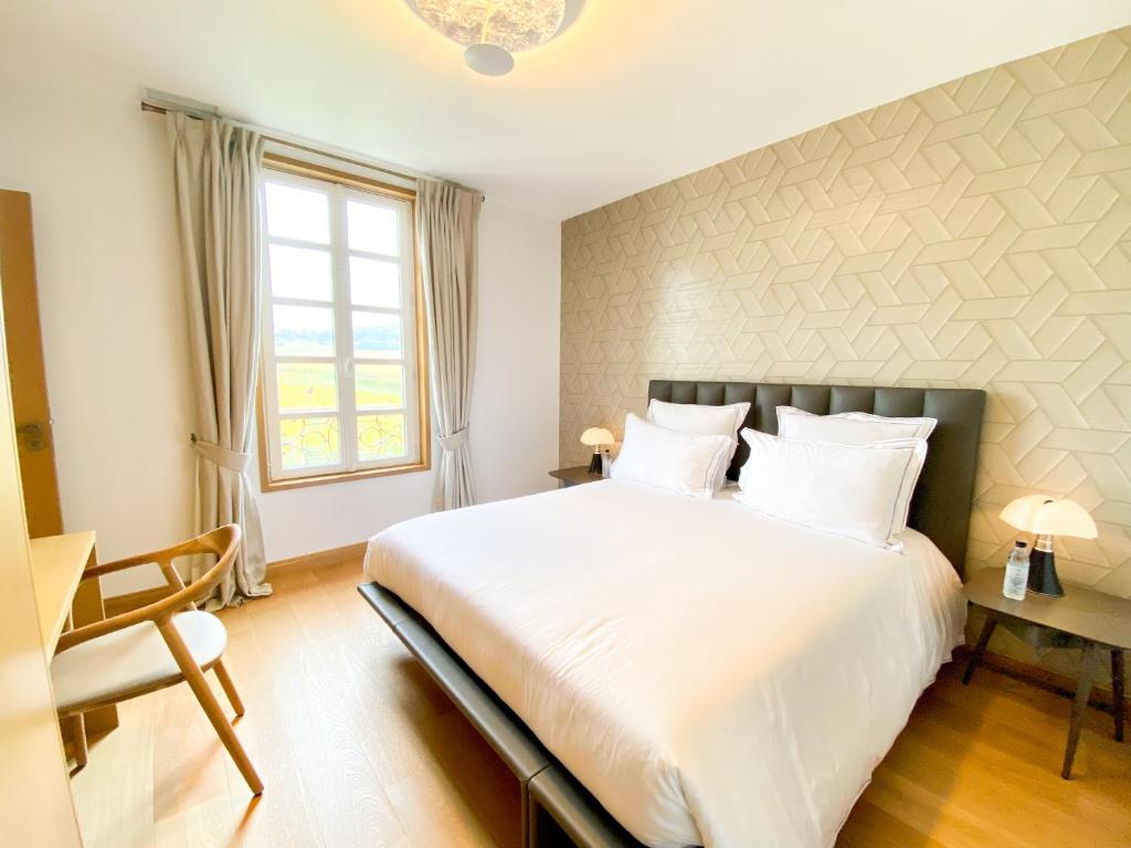 a bedroom with a large white bed and a window at Petit Monlot - Saint-Emilion in Saint-Émilion