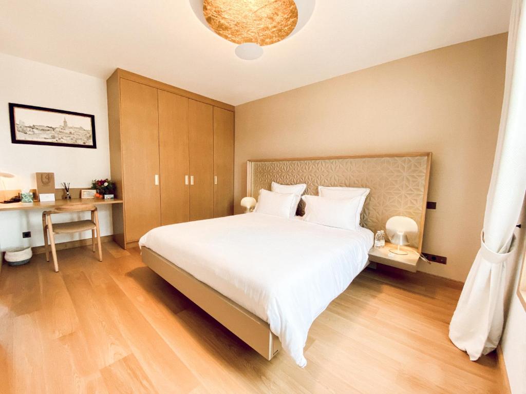 a bedroom with a large white bed and a desk at Petit Monlot - Saint-Emilion in Saint-Émilion