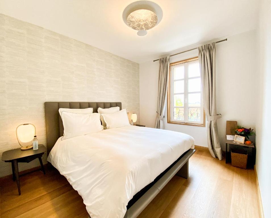 a bedroom with a large white bed and a window at Petit Monlot - Saint-Emilion in Saint-Émilion