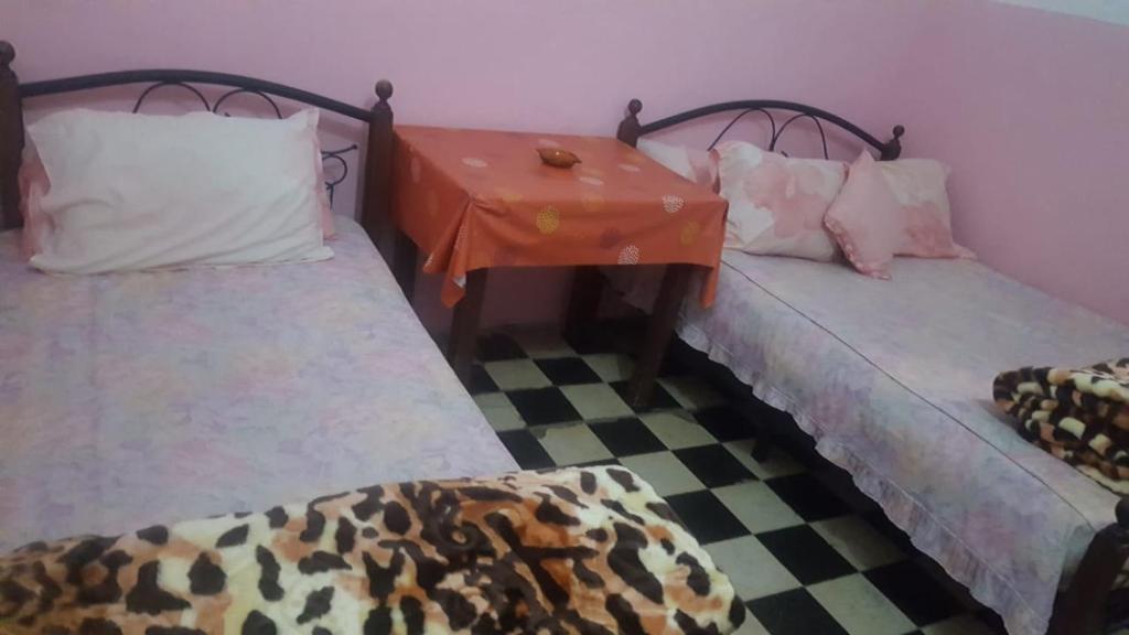 2 camas en una habitación con suelo a cuadros en Hôtel Glacier en Fez
