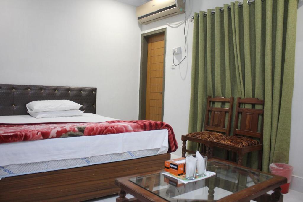 Un dormitorio con una cama y una mesa con un Sidx Sidx de cristal en Pakistan Club Inn Hotel, en Kalar Goth