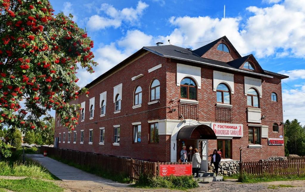 a large brick building with people standing outside of it at Hotel Solovetskaya Sloboda in Solovetsky Islands