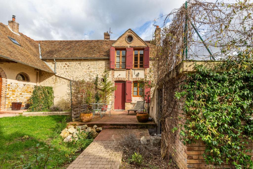 uma velha casa de tijolos com uma porta vermelha em La Bourguignonne 