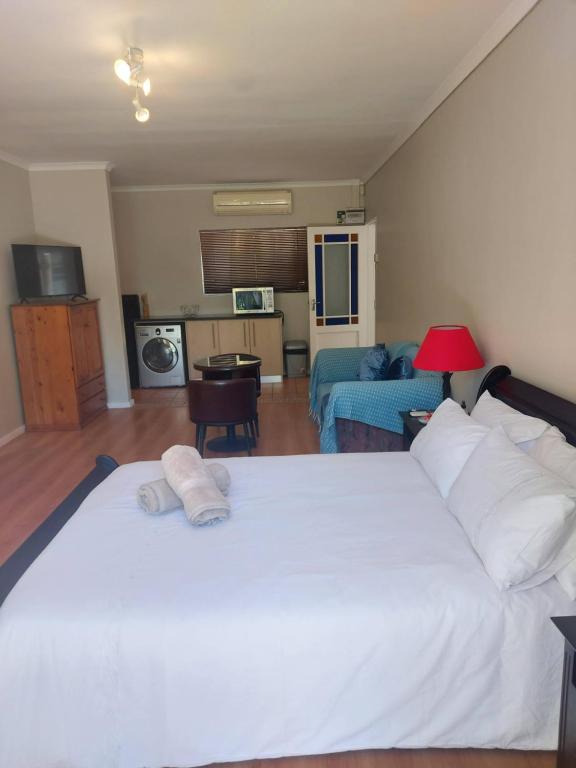 Mimosa Self-Catering Studio Durbanville في دوربانفيل: غرفة نوم بسرير ابيض كبير وغرفة معيشة