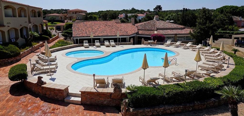 a beach with a pool, chairs, and tables at Hotel Nibaru in Porto Cervo