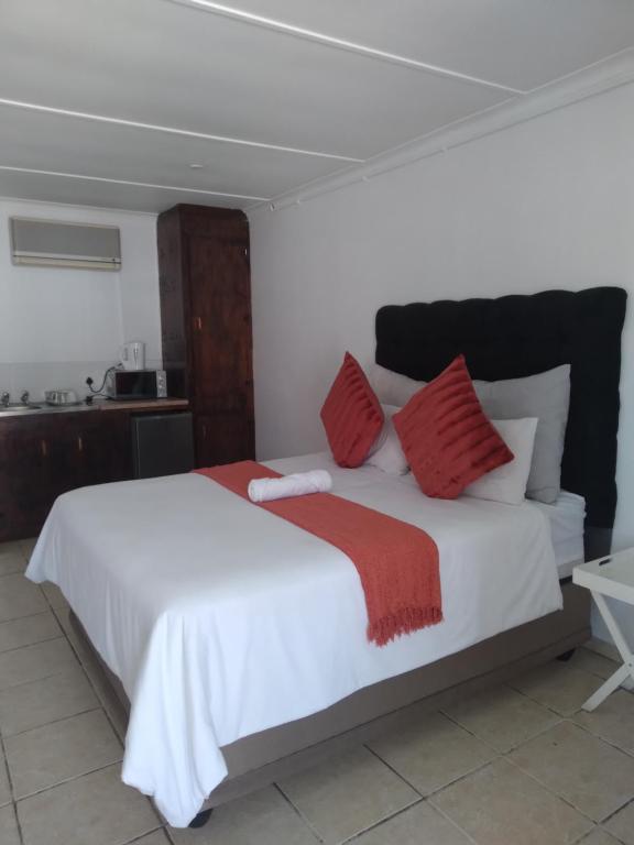 a bedroom with a large white bed with red pillows at Jnc Lodge in Richards Bay