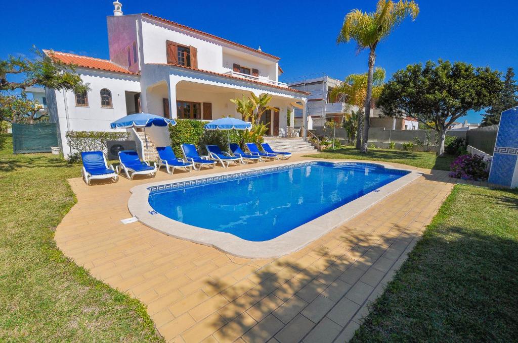 a villa with a swimming pool in front of a house at Casa das Palmeiras by OCvillas in Albufeira