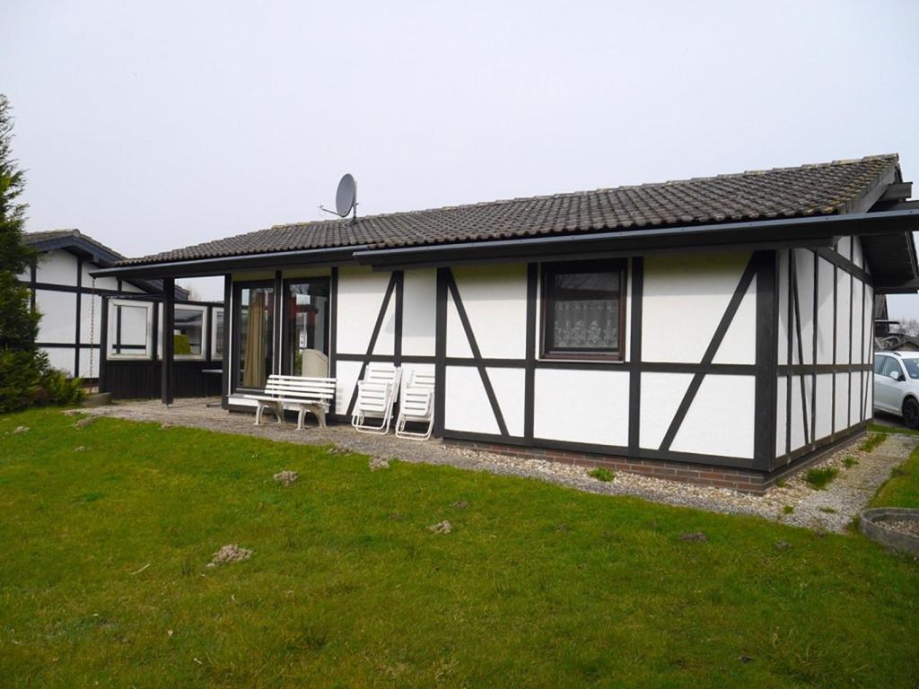 ein weißes und schwarzes Haus mit zwei Stühlen und einem Hof in der Unterkunft Bungalow M 43 in Burhave in Burhave