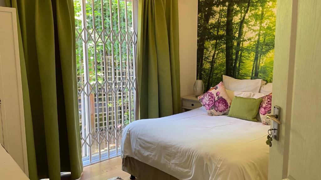 a bedroom with a bed and a large window at Victorian Beach Cottages in Amanzimtoti