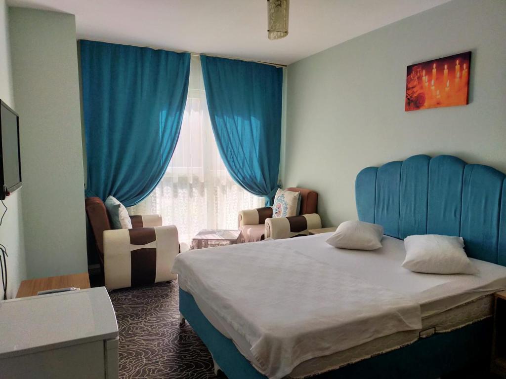 a bedroom with a bed and blue curtains and a window at The Tuyap Rainbow Suites in Beylikduzu