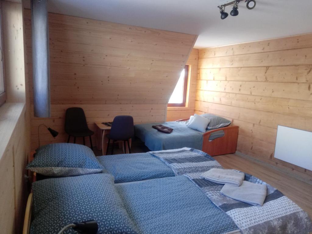 Miodowa Chata Pokoje Gościnne في بوستريك: غرفة نوم بسريرين وطاولة وكراسي