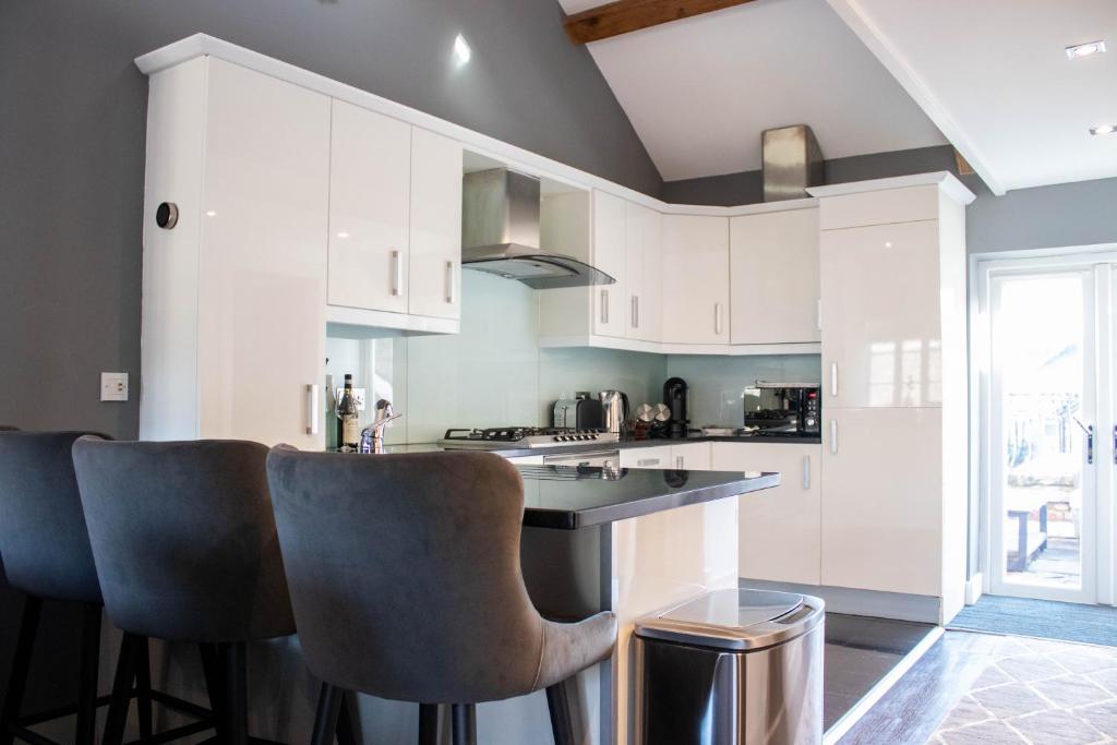 a kitchen with white cabinets and bar stools at Tiger Roof Terrace Lymm in Lymm