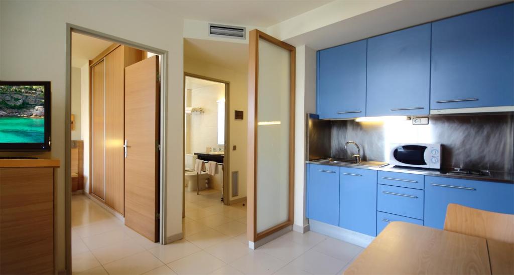 a kitchen with blue cabinets and a television at AQUA Hotel Nostre Mar Apartments in Pineda de Mar