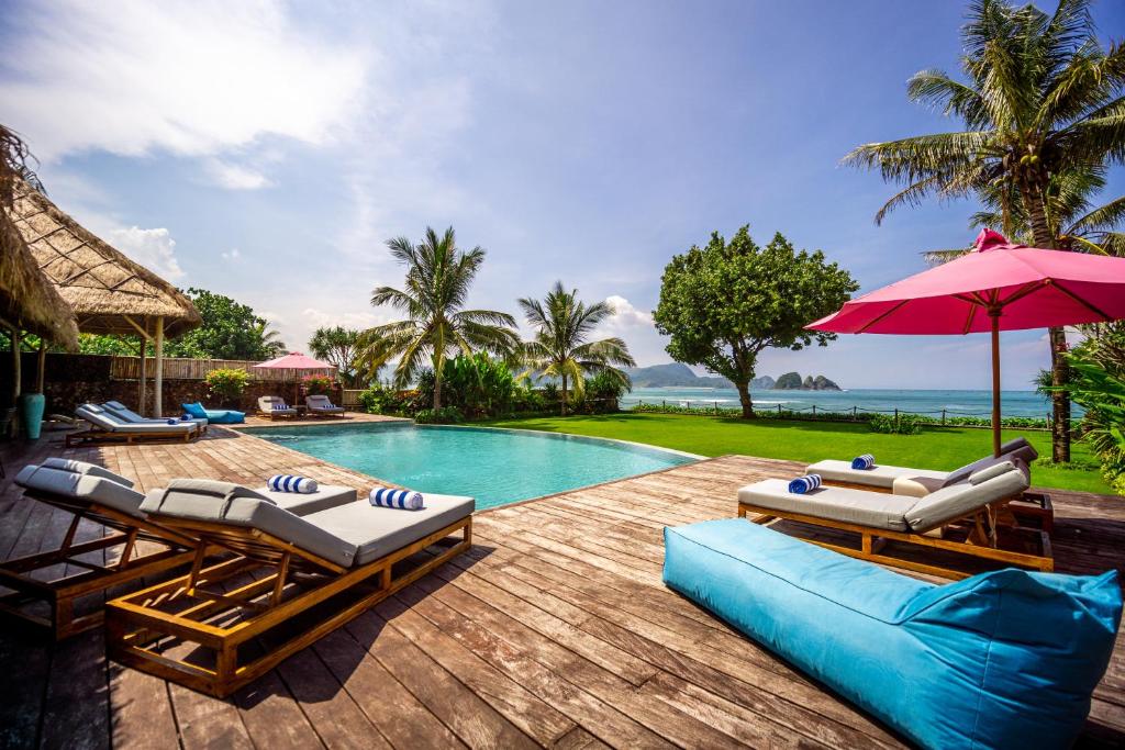 a swimming pool with lounge chairs and an umbrella at Villa Jac in Selong Belanak