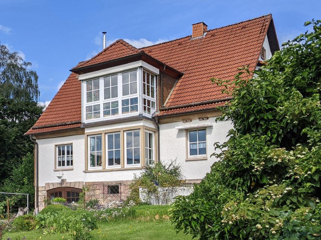 uma grande casa branca com um telhado vermelho em Familienferienwohnung Villa Zaunkönigin em Bischofsheim an der Rhön
