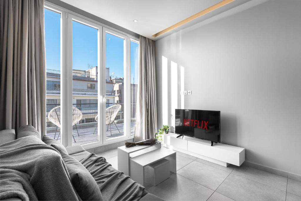 uma sala de estar com televisão e uma grande janela em Penthouse Apartments, The Luxury Suites em Tessalônica
