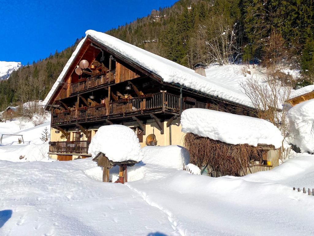 a snow covered log cabin with people on the balcony at Chalet Marie in Flumet