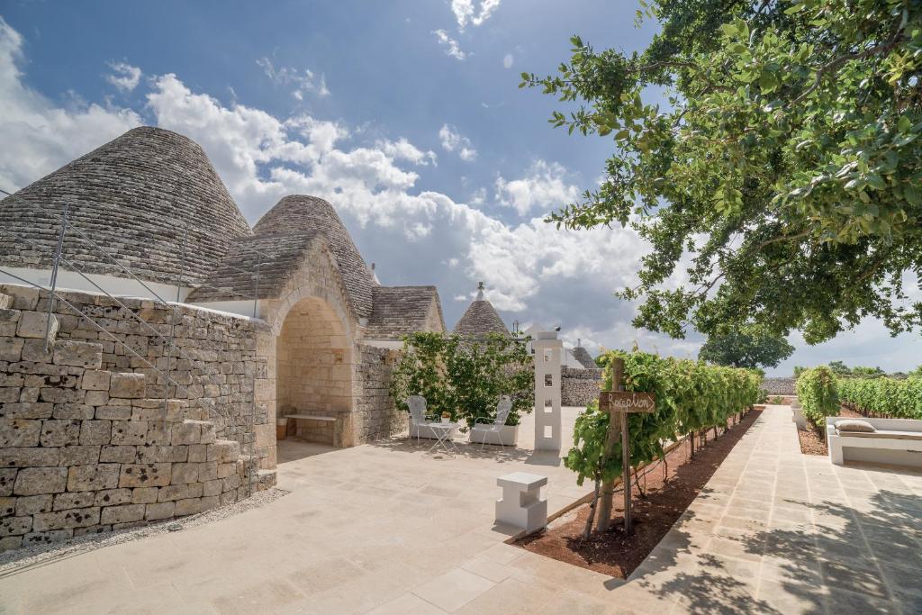 uma vista exterior de um edifício de pedra com videiras em Nina Trulli Resort em Selva di Fasano