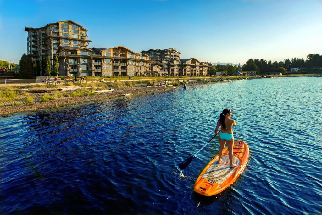 Eine Frau auf einem Paddelbrett im Wasser. in der Unterkunft The Beach Club Resort — Bellstar Hotels & Resorts in Parksville