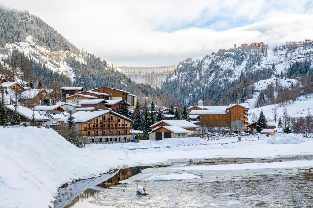 a town covered in snow next to a river at Hotel Tetras Lodge in Tignes