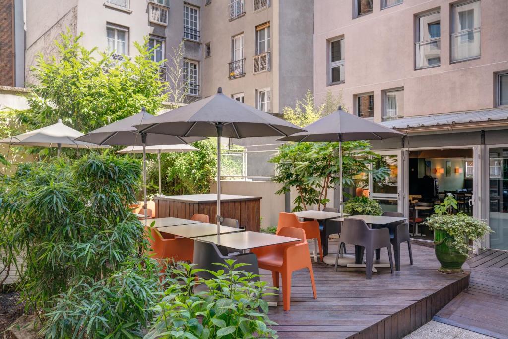 un patio extérieur avec des tables, des chaises et des parasols dans l'établissement Belambra City - Magendie, à Paris