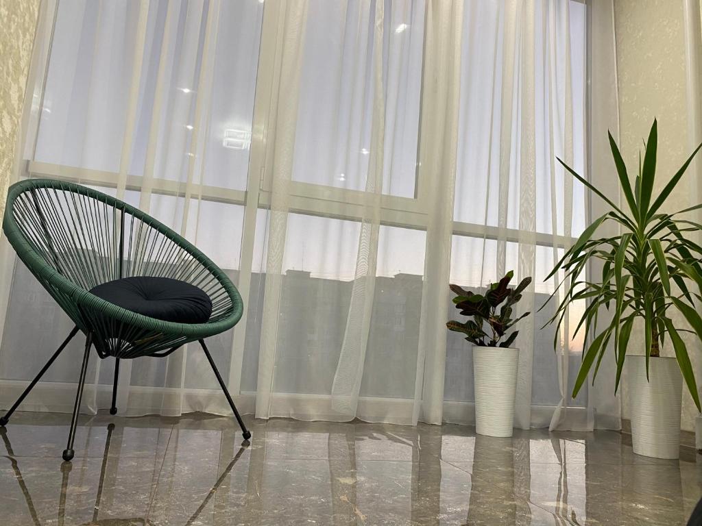 una silla verde sentada frente a una ventana en Люкс апартаменты .РАЙОН АВТОВОКЗАЛА,в ЖК Арена en Rivne