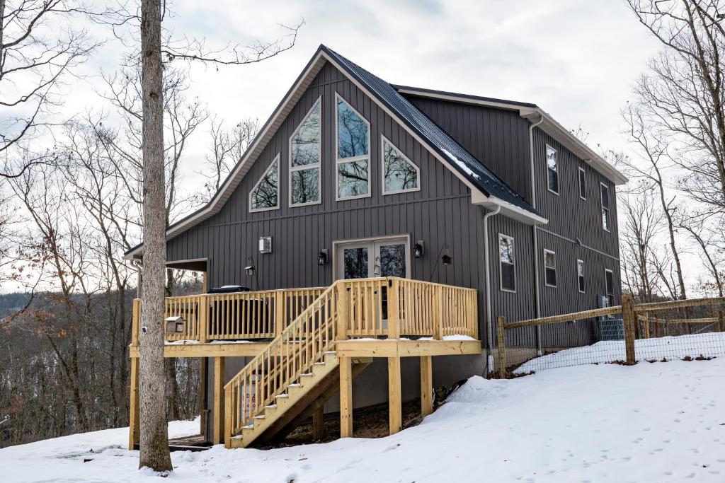 ein schwarzes Haus mit einer Terrasse im Schnee in der Unterkunft NEW!! House Near Raystown Lake in Peaceful Wooded Area in Huntingdon