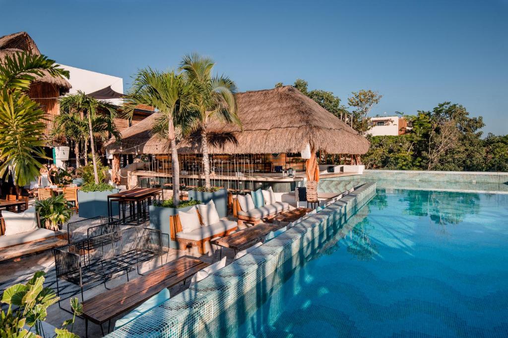 una piscina en un complejo con sillas y un bar en Mayan Monkey Tulum en Tulum