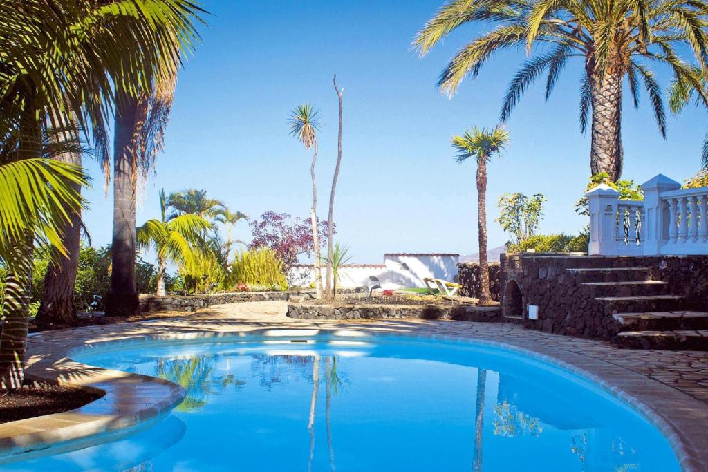 a swimming pool with palm trees and a house at Holiday resort Grandiosa El Paso in El Paso