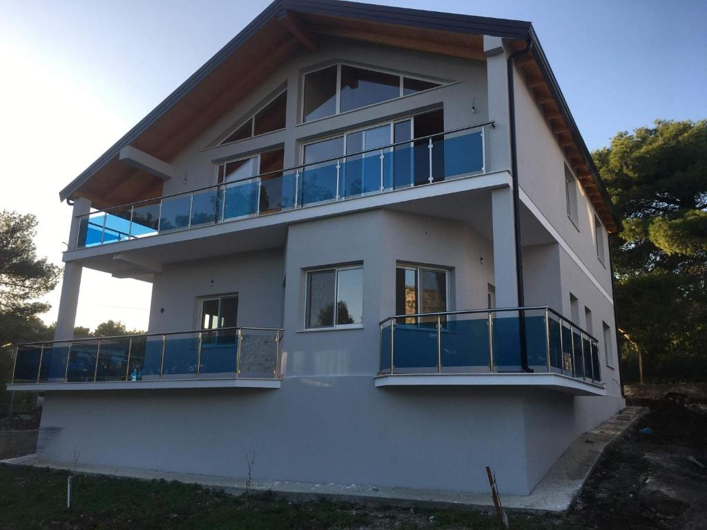 ein weißes Haus mit blauen Balkonen darauf in der Unterkunft Benjy’s Villa(B&B) in Shëngjin