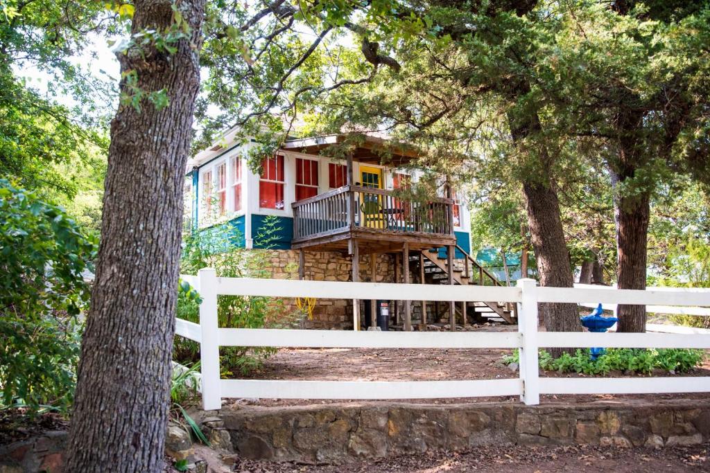 una casa en el bosque con una cerca blanca en The Bluebird Cottage Style Cabin with Hot Tub near Turner Falls and Casinos en Davis